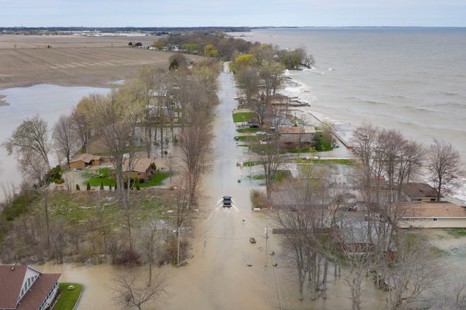 A truck slowly drives through a flooded Cotterie Park Road in Leamington, Ontario, on May 8, 2019, as waves from Lake Erie batter the shoreline.