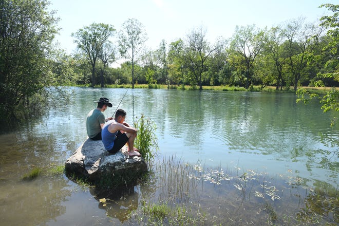 Michael Truesdell and Nathaniel Cecil of Lincoln Park fish from a rock surrounded by water near the usual bank of the Trenton Channel in Elizabeth Park.
