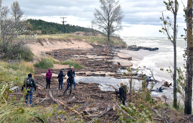 People assess the damage on the beach at Point Betsie Lighthouse, north of Frankfort, on Oct. 16, 2019, after gale-force winds on Lake Michigan pushed near-record-high water onto the beach along with a huge amount of woody debris. As winter approaches, lakeside residents know that storms could bring more coastal flooding, erosion, ice floes and jams that could create havoc.