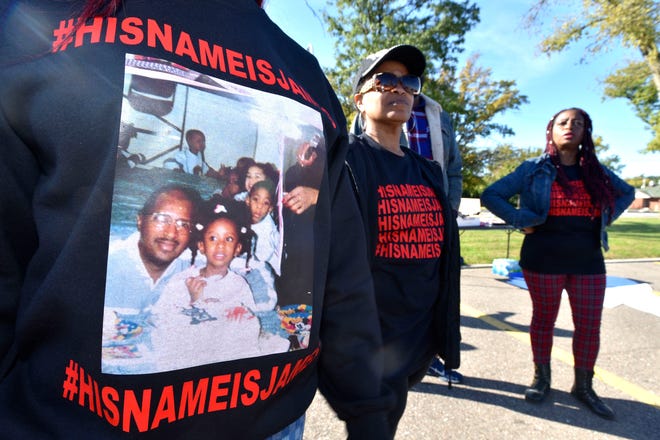 Paige White, left, 28, wears a picture of her sitting on the lap of her father, James White, on her fourth birthday as she stands with her aunt Mary Murray, center, and her mother, Martha Chambers, all of Inkster, before they march. Murray and Chambers are twin sisters, both 59.