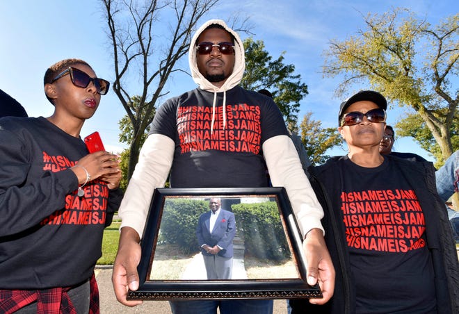 James White's daughter, Chanelle White, left, 27, and her aunt Mary Murray, both of Inkster, stand with Chanelle's brother, Joseph White, center, 25, of Wayne, as he holds a picture of their father, James White.