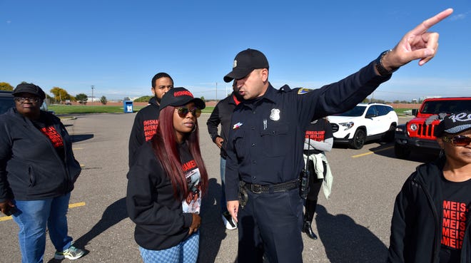 Paige White, left, 28, talks with a Dearborn Heights police officer before her family members and loved ones march to Beaumont Hospital on Oakwood.