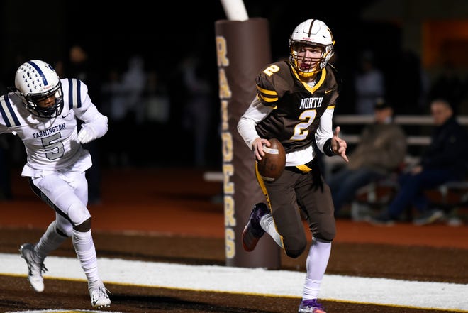North Farmington quarterback Jacob Bousamra, right, tries to run out the clock in the end zone as he is chased by Farmington defenseman T ’ Sean Sample but is sacked for a safety with less than a minute in the fourth quarter.