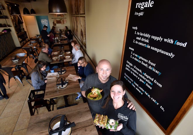 Co-owners Shawn and Rachelle Mckerness pose with Malaysian BBQ wings and wonton tuna tacos, respectively, in the front of their restaurant.