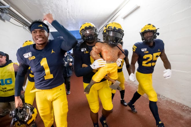From left, Michigan defensive back Ambry Thomas, linebacker Devin Gil and running back Hassan Haskins carry the Paul Bunyan trophy up the tunnel after the 44-10 win over Michigan State on Saturday, Nov. 16, 2019 at Michigan Stadium in Ann Arbor.