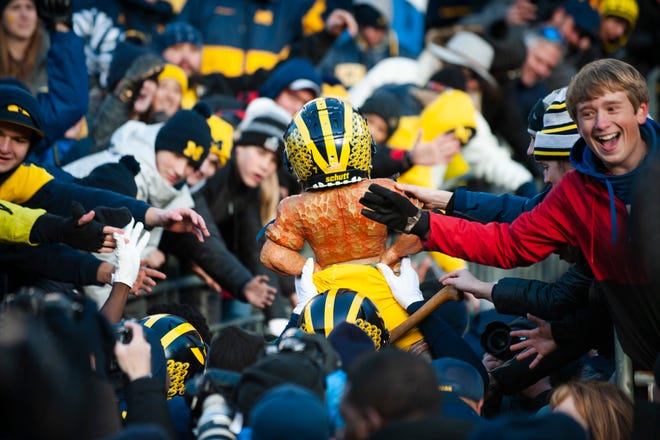 Michigan players carry the Paul Bunyan Trophy (sporting yellow pants and a winged helmet) into the tunnel to the delight of the home fans after a decisive 44-10 victory over Michigan State.