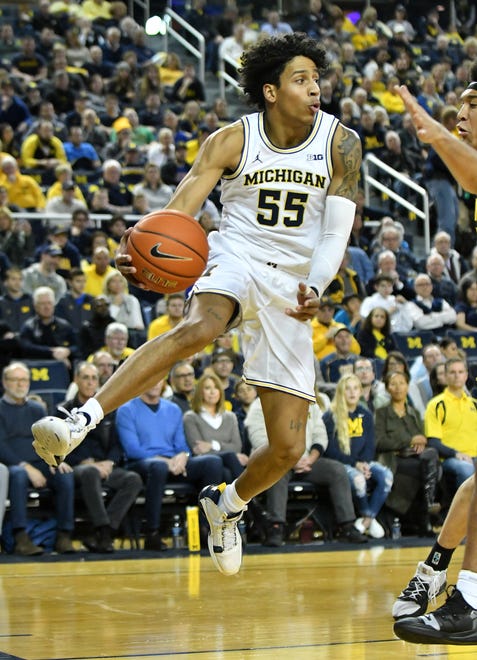 Michigan guard Eli Brooks (55) makes an airborne pass in the first half.