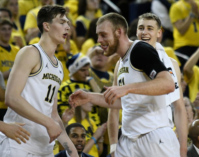 Michigan forward Colin Castleton (11) and guard Franz Wagner (21) react with forward Austin Davis (51) as he comes to the bench in the second half.
