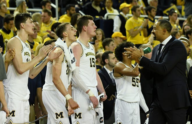 Michigan head coach Juwan Howard, right, fires up the bench in the second half.  From left is forward Colin Castleton (11), guard Franz Wagner (21) and center Jon Teske (15) .