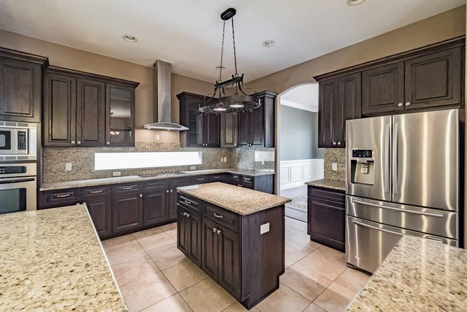 The gourmet kitchen includes granite countertops, dark wood cabinets, stainless steel appliances, an island, breakfast bar and dine-in space.