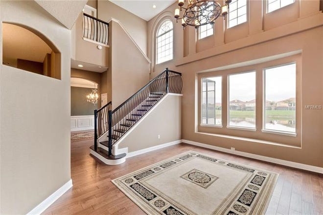 The foyer features soaring ceilings and leads to a master suite with private access to the pool.