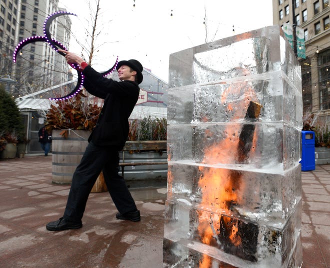 Eric Scott Baker, of Detroit, spins lighted s-staffs behind a Fire and Ice Tower. Baker is a performer with the Detroit Circus as the ice sculpture was built by US Ice Carvings employee Chad Pisarsk (not pictured).