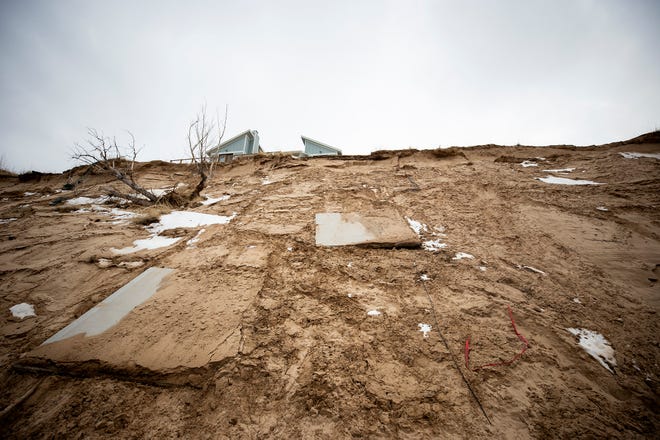 Large sections of concrete patio slide down the bluff toward the icy waters of Lake Michigan below as erosion threatens homes in Shelby, Mich.