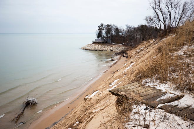 A wooden walkway drops off the bluff after the remainder of it has fallen into Lake Michigan along what used to be North Lakeshore Drive at Juniper Beach in Golden Township.