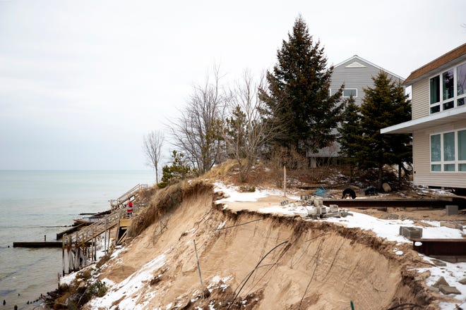 Norma Mendenhall (red coat), 88, takes a photo of her home as she stands on a staircase leading down to Lake Michigan in Shelby, south of Ludington. Norma has lived here for 58 years but now bluff erosion threatens to destroy her home and those of her neighbors.