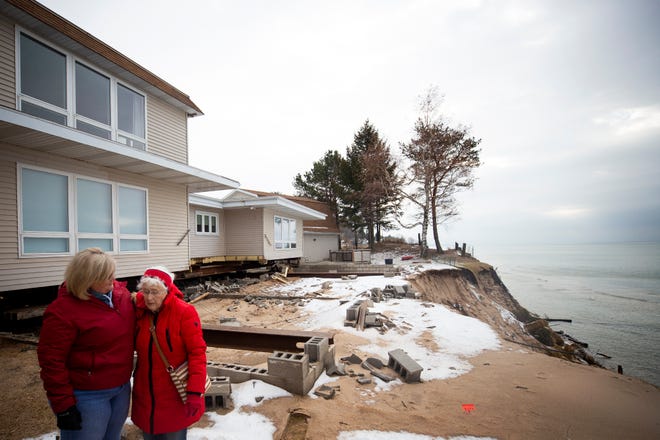 Dawn Mendenhall embraces her mother Norma Mendenhall after looking at the erosion that high lake levels have caused on her property on the Lake Michigan shoreline in Shelby, Mich. Norma Mendenhall has lived in the home for 58 years. The home has been moved back from the edge of the bluff to protect it from sliding into the lake.