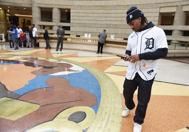 Tigers player Troy Stokes Jr. takes photos of iconic african american figures on the ring of genealogy floor installation in the rotunda at the Charles H. Wright Museum of African American History.