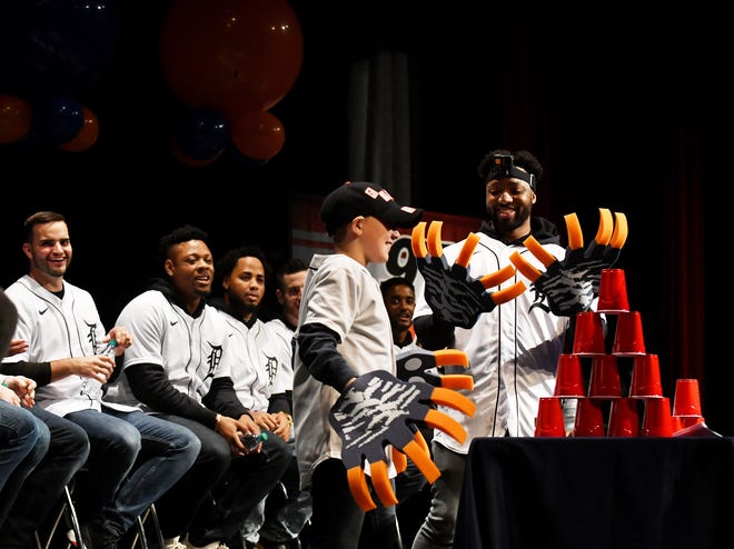 Tigers outfielder Cristin Stewart, right, looks down at his Tiger claw hands after Domonic Hamden, 10, of St. Clair Shores, left, won the race to make a tower with plastic cups while wearing the claws.