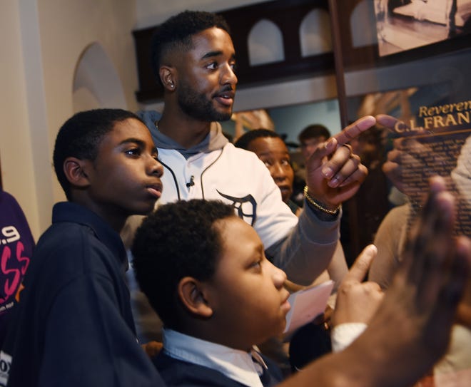 Tigers player Niko Goodrum points to a clue with team members Nathaniel Collins,12, and Ian Polk, 11, during a informational treasure hunt game inside the "And Still We Rise" exhibit at the Charles H. Wright Museum of African American History.