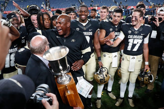 Colorado head coach Mel Tucker, left, celebrates with his players after receiving the Centennial Cup for defeating intrastate rival Colorado State in Aug. 30, 2019, in Denver. Colorado won 52-31.