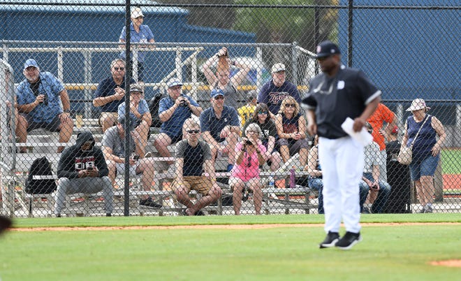 Fans watch Tigers players workout under the instruction of bench coach Lloyd McClendon, right.