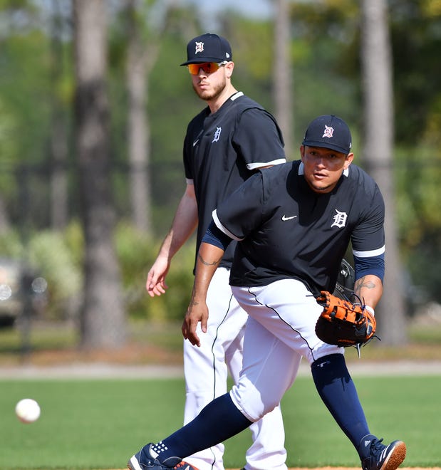 Tigers' C.J. Cron, background, watches while Miguel Cabrera fields a ground ball.