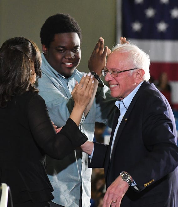 Bernie Sanders shakes hands and hugs guests on stage after he finished speaking at the rally in Detroit.