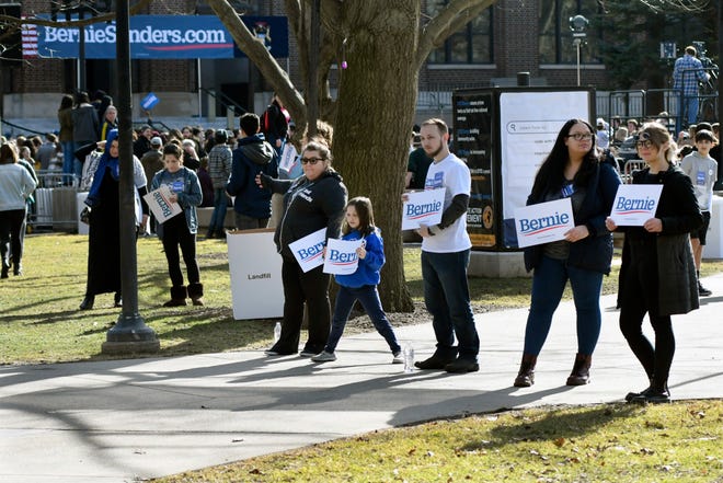 Volunteers point the way to the main stage where supporters can see U.S. Senator and presidential candidate Bernie Sanders, Sunday, March 8, 2020 in Ann Arbor, Mich.