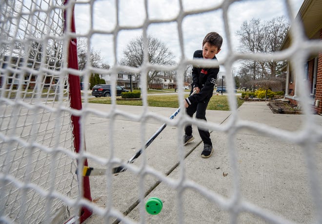 Ian Mearns, 9, practices his shot in front of his home in Grosse Ile. The Meridian Elementary School fourth-grader is a member of the Belle Tire Bombers hockey team and was trying to get in some practice after his season was postponed due to the coronavirus pandemic.