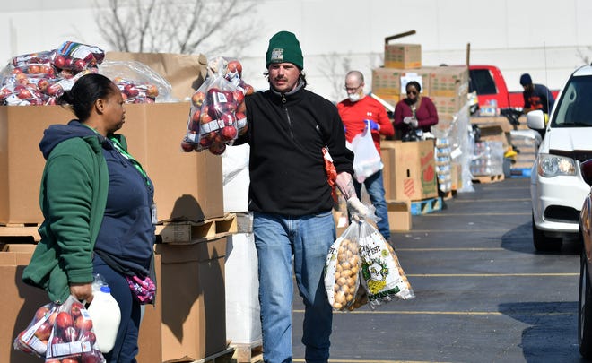 From left, Verly Sutton, 49, and T.J. Robinson, 41, both of Detroit and with Gleaners, move food to the vehicles and walk up residents.  Gleaners Community Food Bank operates a drive thru and walk up food drive in Southwest Detroit near the Clemente Recreation Center in Detroit on Mar. 25, 2020.  Gleaners had an entire semi trailer of food which would cover approximately 600 households or families.