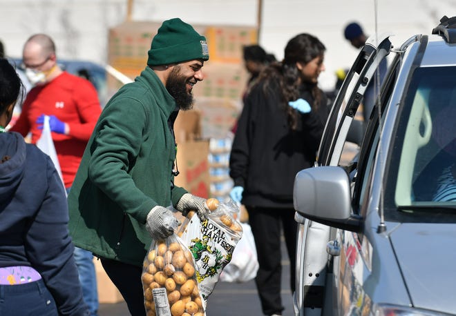 Andre Peterson, 36, of Harper Woods gets bags of potatoes to a family's vehicle. Gleaners Community Food Bank operates a drive-thru and walk-up food drive in southwest Detroit near the Clemente Recreation Center in Detroit on March 25, 2020.  Gleaners had an entire semi trailer of food, enough for approximately 600 households or families.