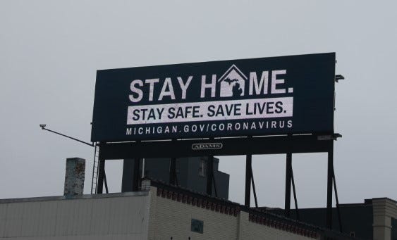 An electronic billboard in downtown Lansing encourages residents to "stay home" amid the COVID-19 pandemic.