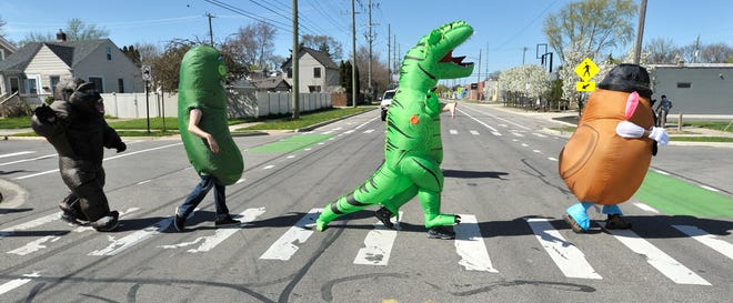 Characters walk on Spencer as they cross Hilton. Members of the Ferndale T-Rex Walking Club put on their inflatable costumes and get exercise while walking around the south end of Ferndale, Friday afternoon, May 1, 2020. All the while social distancing, they hope to bring cheer to neighbors along the route.