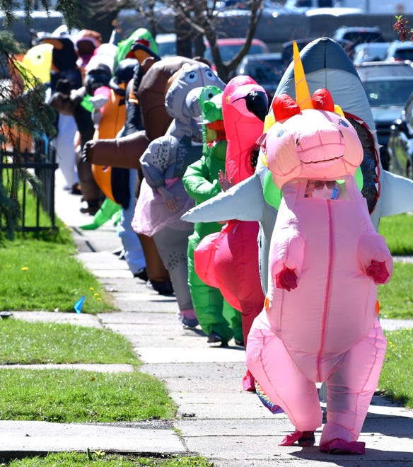 Group founder and unicorn Sarah Ignash, of Ferndale, leads the walk through the neighborhood on Spencer. Members of the Ferndale T-Rex Walking Club put on their inflatable costumes and get exercise while walking around the south end of Ferndale, Friday afternoon, May 1, 2020. All the while social distancing, they hope to bring cheer to neighbors along the route.