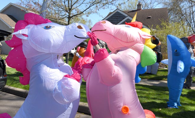 Group founder  and unicorn Sarah Ignash, right, of Ferndale, helps Rebecca Ewald, of Hazel Park, get a handle on her unicorn costume before the walk. Members of the Ferndale T-Rex Walking Club put on their inflatable costumes and get exercise while walking around the south end of Ferndale, Friday afternoon, May 1, 2020. All the while social distancing, they hope to bring cheer to neighbors along the route.