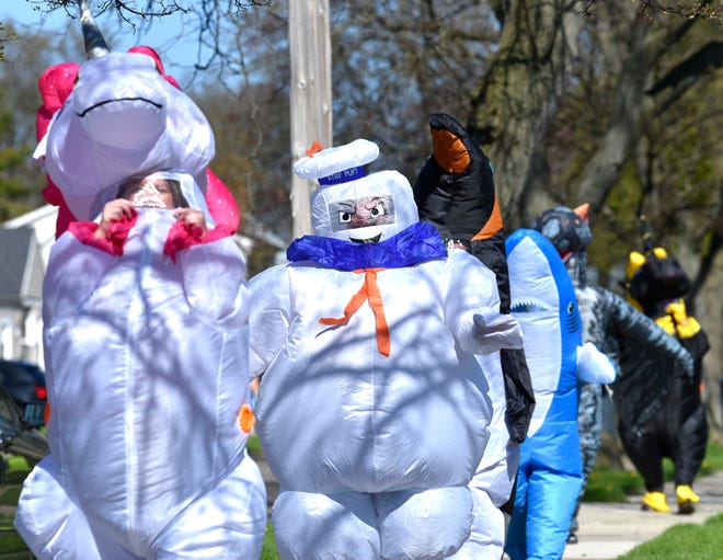 Characters follow each other through the neighborhoods. 
Members of the Ferndale T-Rex Walking Club put on their inflatable costumes and get exercise while walking around the south end of Ferndale, Friday afternoon, May 1, 2020. All the while social distancing, they hope to bring cheer to neighbors along the route.