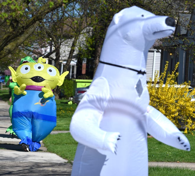 Characters follow each other through the neighborhoods as members of the Ferndale T-Rex Walking Club put on their inflatable costumes and get exercise while walking around the south end of Ferndale, Friday afternoon, May 1, 2020. All the while social distancing, they hope to bring cheer to neighbors along the route.