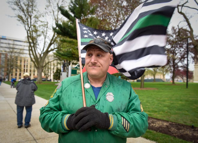 Warren city councilman Eddie Kabacinski holds a flag during a protest at the state Capitol to oppose the executive orders Gov. Gretchen Whitmer issued in response to the coronavirus pandemic, Thursday, May 14, 2020.