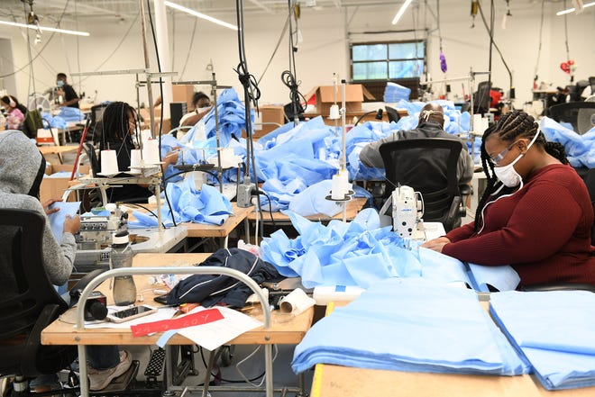 Seamstress Marie Dobine, 23, of Detroit, right, sews medical isolation gowns at Empowerment Plan in Detroit on May 14, 2020.