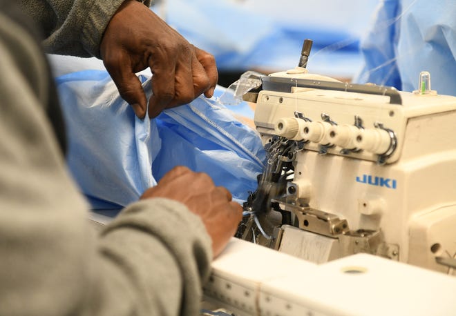 Inventory and logistics specialist Aaron Branch, 50, of Detroit sews the sleeves onto the medical isolation gowns at Empowerment Plan in Detroit on May 14, 2020.