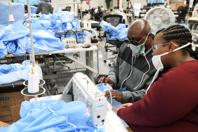 Stitcher Labrita Dobine, 23, right, consults inventory and logistics specialist Aaron Branch, 50, both of Detroit on part of the gown she is sewing at Empowerment Plan in Detroit on May 14, 2020.