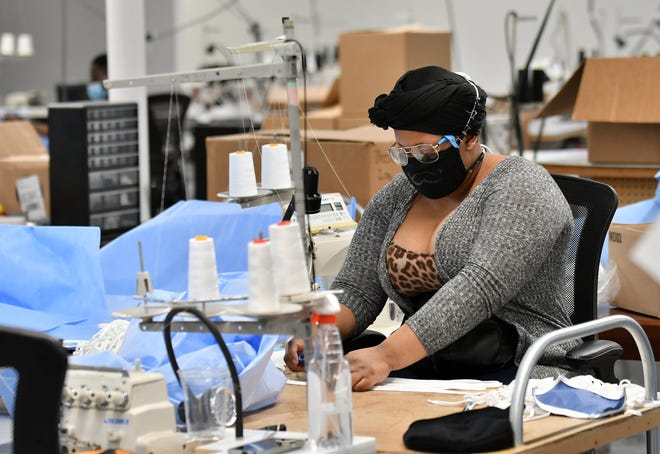 Seamstress Asia Taylor, 22, of Detroit sews straps on medical isolation gowns at Empowerment Plan in Detroit on May 14, 2020.