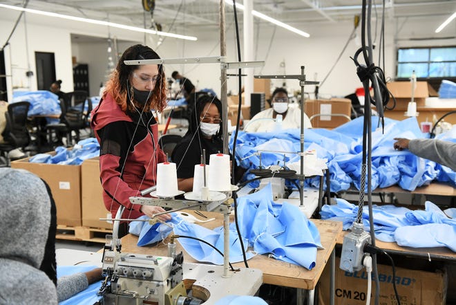 From left, Seamstresses Morgan Ealy, 25, bottom left, Jessica West, 27, and Angel Tyler, 34, all of Detroit discuss the material that the medical isolation gowns are made from at Empowerment Plan in Detroit on May 14, 2020.