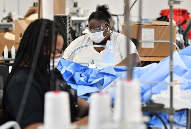 From left, Seamstresses Angel Tyler, 34, and Amber Hinton, 26, both of Detroit sew medical isolation gowns at Empowerment Plan in Detroit on May 14, 2020.