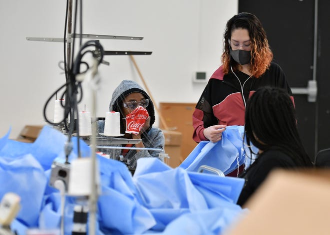 From left, Seamstresses Morgan Ealy, 25, and Jessica West, 27, both of Detroit discuss the material that the medical isolation gowns are made from at Empowerment Plan in Detroit on May 14, 2020.