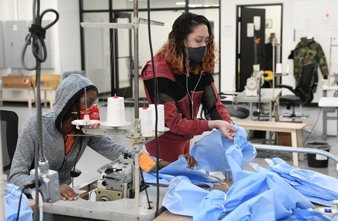 From left, Seamstresses Morgan Ealy, 25, and Jessica West, 27, both of Detroit discuss the material that the medical isolation gowns are made from at Empowerment Plan in Detroit on May 14, 2020.