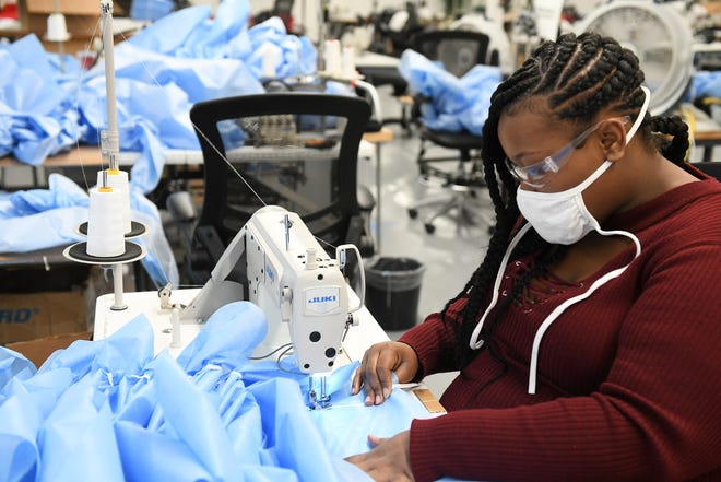 Stitcher Labrita Dobine, 23, right, of Detroit sews medical isolation gowns at Empowerment Plan in Detroit on May 14, 2020.
