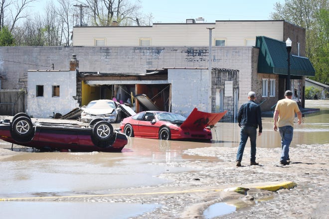 Cars are scattered and flipped over on the main street, West Saginaw, in the Village of Sanford after flood waters swept through the town.