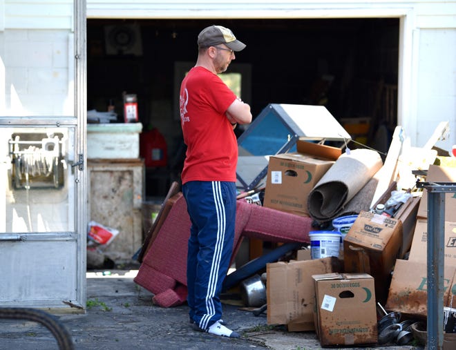 Shaun Johnson, of Dewitt, looks down as he says he doesn't want to cry as he and family members remove items out the basement of his flooded family cottage.