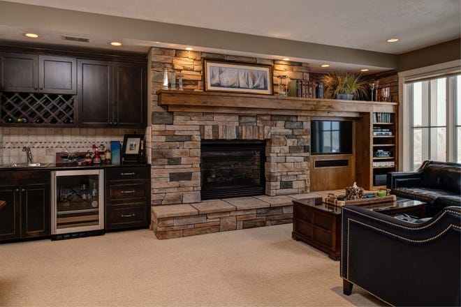 A family room with a stone fireplace and bar.